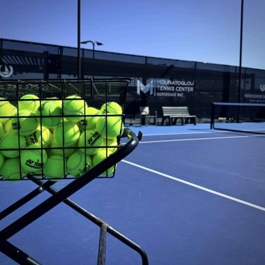 Basket of tennis balls on a court at Mouratoglou Tennis Center Horseshoe Bay.