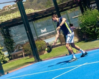 Player hitting a padel shot at Mouratoglou Tennis Center Cala di Volpe in Sardinia.