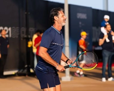 Patrick Mouratoglou smiling in ready position holding a tennis racket on a court at Mouratoglou Tennis Center Hudayriyat Island in Abu Dhabi.