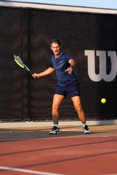 Patrick Mouratoglou hitting a forehand on a tennis court at Mouratoglou Tennis Center Hudayriyat Island in Abu Dhabi.