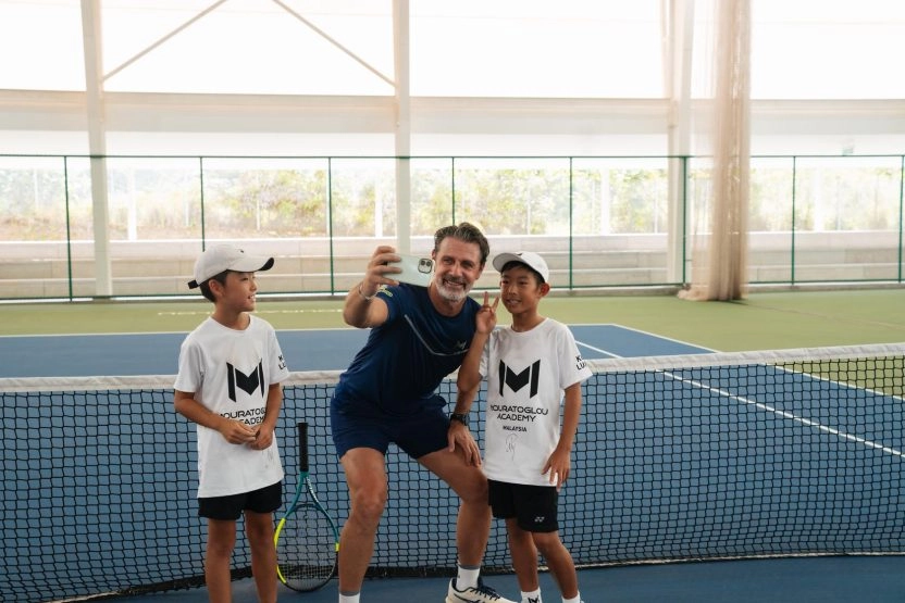 Patrick Mouratoglou taking a selfie with students on an indoor tennis court at Mouratoglou Academy Malaysia on the campus of Epsom College in Malaysia.