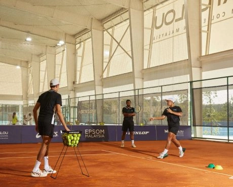 Players practicing on indoor clay tennis courts during a coaching session at Mouratoglou Academy Malaysia.