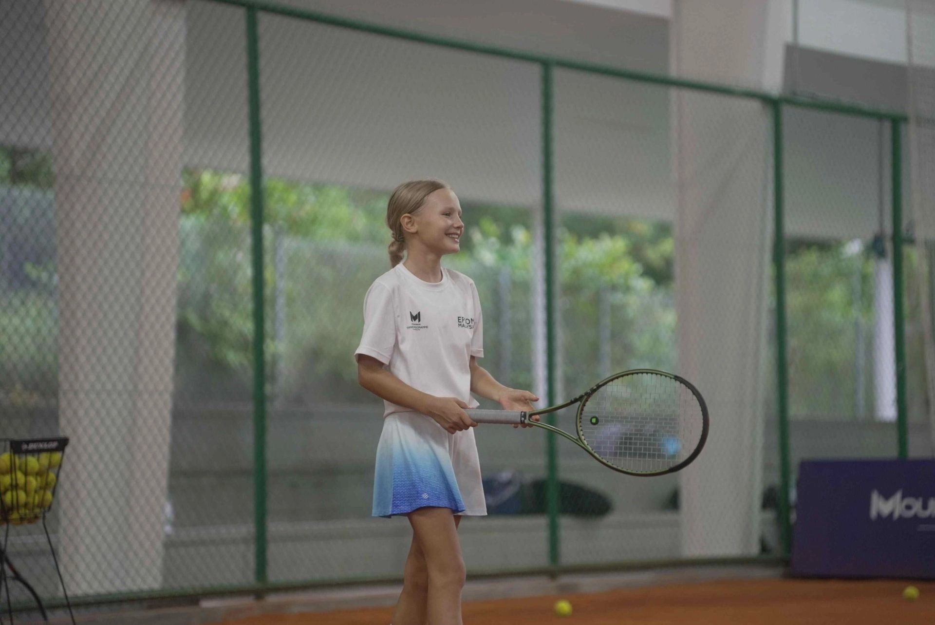 Young girl holding a tennis racket on an indoor clay court at Mouratoglou Academy Malaysia on the campus of Epsom College in Malaysia.
