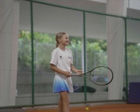 Young girl holding a tennis racket on an indoor clay court at Mouratoglou Academy Malaysia on the campus of Epsom College in Malaysia.