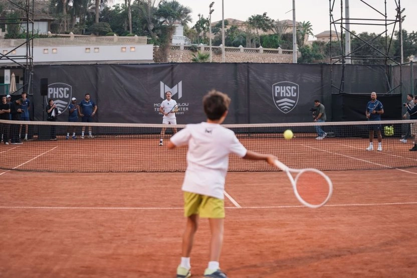 Young player hitting a forehand against Patrick Mouratoglou on a clay court at Mouratoglou Tennis Center Palm Hills, Egypt