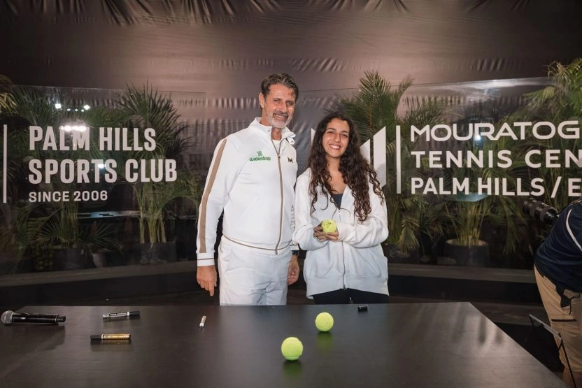 Patrick Mouratoglou posing with a young player holding a signed tennis ball at Mouratoglou Tennis Center Palm Hills, Egypt
