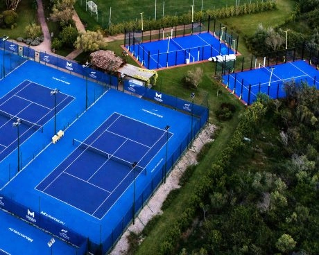 Aerial view of the outdoor padel and tennis courts at M Padel Sardinia, surrounded by landscaped greenery and premium sports facilities.