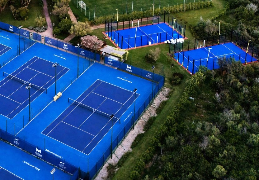 Aerial view of the outdoor padel and tennis courts at M Padel Sardinia, surrounded by landscaped greenery and premium sports facilities.