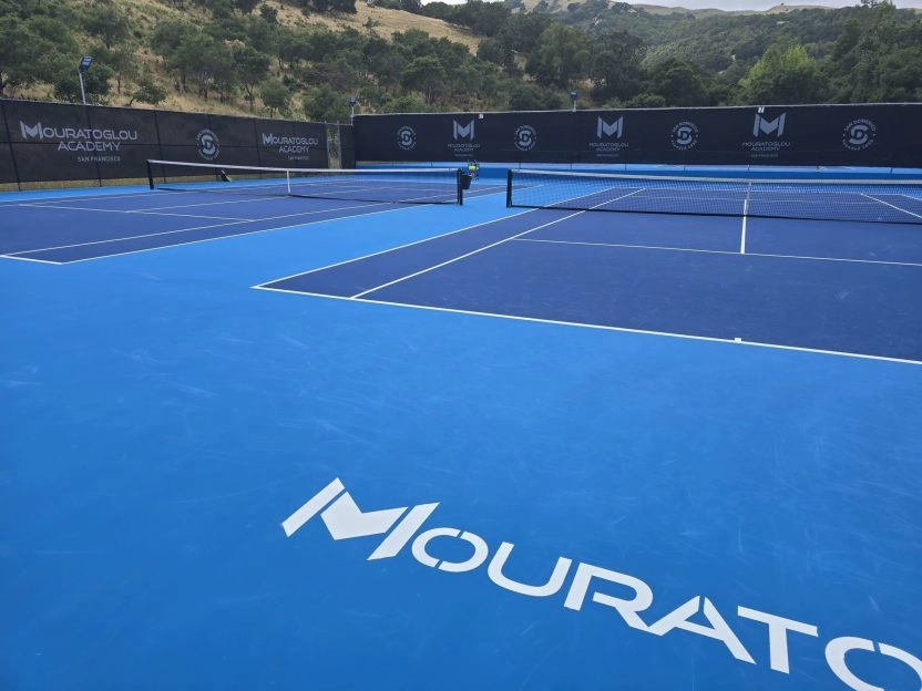 Outdoor hard tennis courts at Mouratoglou Academy San Francisco with blue playing surfaces.