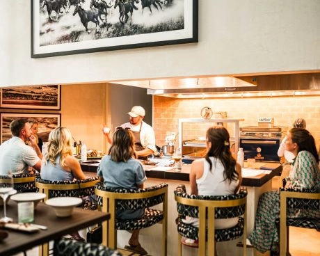 Guests seated around a chef’s table beside an open kitchen at La Estancia, home of Mouratoglou Tennis Center Odessa Midland.