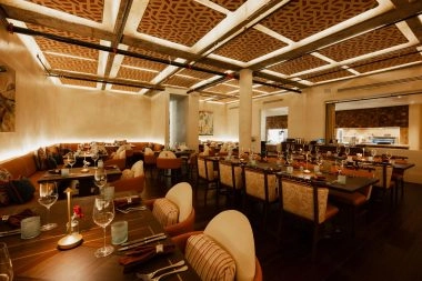 Elegant restaurant dining room with set tables and an open kitchen at La Estancia, home of Mouratoglou Tennis Center Odessa Midland.