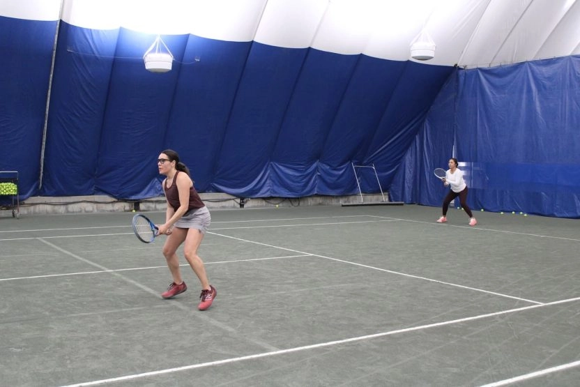 Adult tennis players playing on an indoor court at Mouratoglou Tennis Center Westchester.