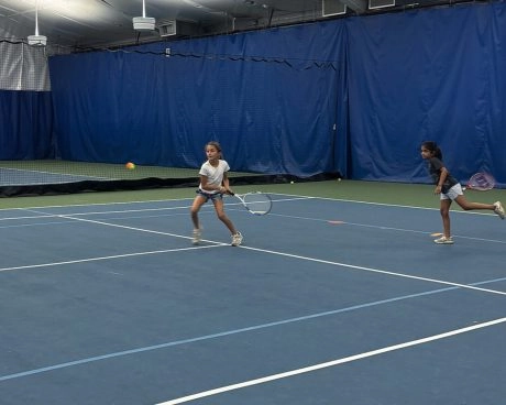 Two young tennis players practicing on an indoor court at Mouratoglou Tennis Center New York.